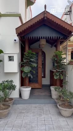 two potted plants in front of a building with a door on the right side