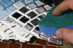 a person is using a sponge to clean the tile on top of a countertop