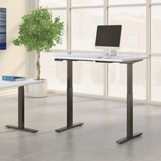 a computer desk sitting in front of a window next to a potted green plant