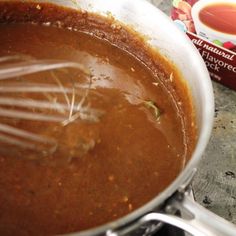 a pot filled with sauce and whisk on top of a stove next to a carton of eggnox