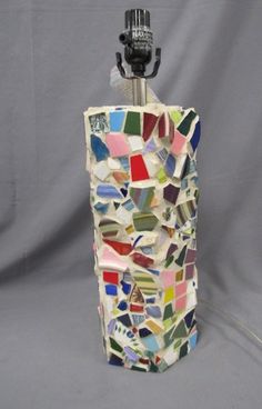 a multicolored mosaic glass bottle with a light on it's side and a camera attached to the top