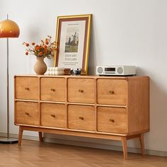 a wooden dresser sitting next to a lamp on top of a hard wood floor