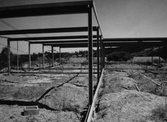 black and white photograph of an empty enclosure in the middle of some grass covered rocks