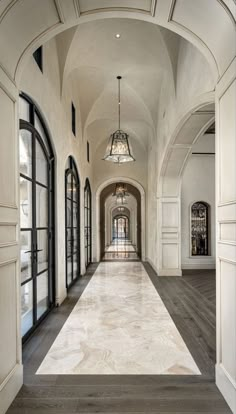 a long hallway with arched doorways and chandelier hanging from it's ceiling