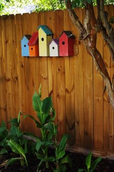 colorful birdhouses on the side of a wooden fence