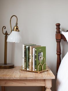 a wooden table with books on it and a lamp next to it in a bedroom