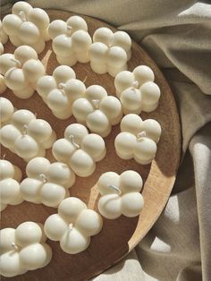 a wooden plate topped with white marshmallows on top of a gray cloth