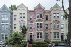 a row of multi - story townhouses with cars parked on the street in front