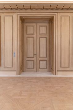 an empty room with wooden doors and parquet flooring in the center, as well as wood paneling on the walls