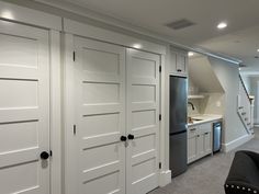 a kitchen with white cabinets and stainless steel appliances in the middle of an open floor plan