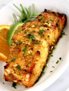 a piece of fish on a white plate with orange slices