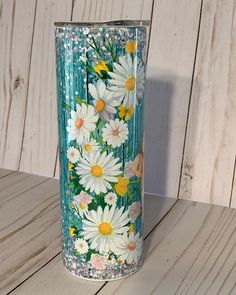 a blue vase with white daisies painted on the outside and yellow flowers in the inside