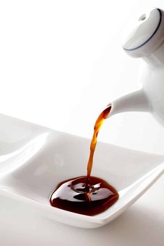 a sauce being poured into a white bowl