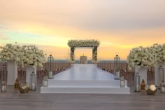 an outdoor wedding setup with white flowers and candles on the steps leading up to the aisle