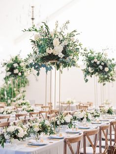 the tables are set up with white flowers and greenery for an elegant wedding reception