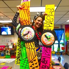 a woman is holding up some colorful clocks