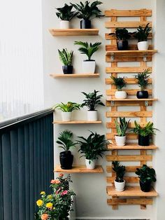 several wooden shelves with potted plants in them on the side of a building,