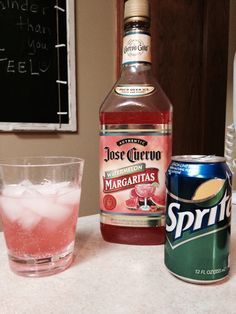 a bottle of rose wine next to a glass with ice and a can of spritz