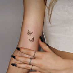 two women with matching tattoos on their arms holding each other's hands and one has a butterfly tattoo on her left arm