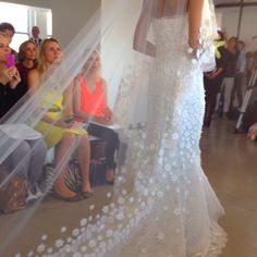 a woman in a wedding dress is walking down the runway with her veil over her head