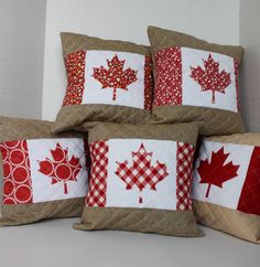 four pillows with red and white quilting on them, each featuring a maple leaf