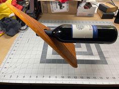 a bottle of wine sitting on top of a piece of wood next to a ruler