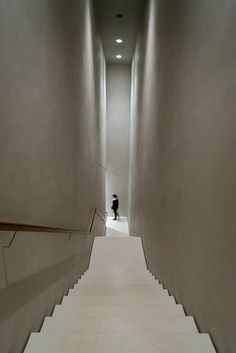 a person is walking down the stairs in an empty building with white walls and carpet