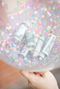 a person holding a bubble filled with money and confetti on top of it