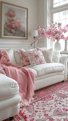 a living room filled with white furniture and pink flowers