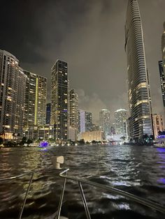 the city skyline is lit up at night as seen from a boat in the water