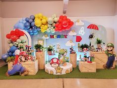 an indoor area with balloons, mario and other decorations on the wall above it is a stage set up for children's birthday celebrations