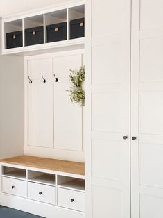 a white mud room with some drawers and cabinets on it's sides, including a coat rack