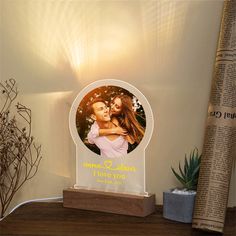 a wooden photo frame with an image of a man and woman in the center on top of a shelf next to a plant