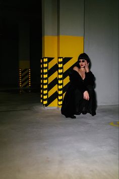 a woman is sitting on the ground talking on her cell phone while wearing a black dress