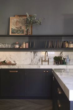 a kitchen with marble counter tops and black cabinets, gold pulls on the cupboards