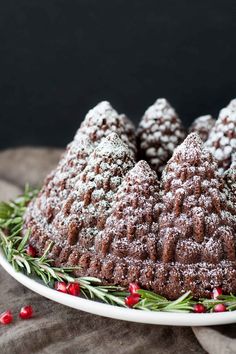 a cake with powdered sugar and cranberries is on a white platter