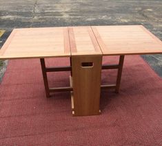 a wooden table sitting on top of a red rug next to a parking lot with no one around it