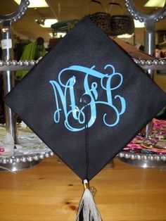 a black graduation cap with blue monogrammed letters and a tassel hanging from it