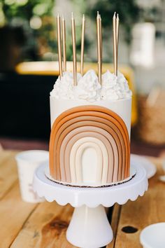 there is a cake with white frosting and rainbow decorations on it, sitting on a wooden table