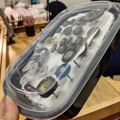 a plastic container filled with lots of different types of hairbrushes on top of a wooden table