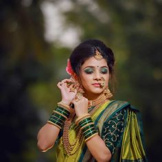 a woman in green and gold outfit with jewelry on her head, posing for the camera