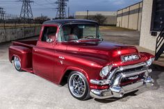 an old red truck parked in a parking lot