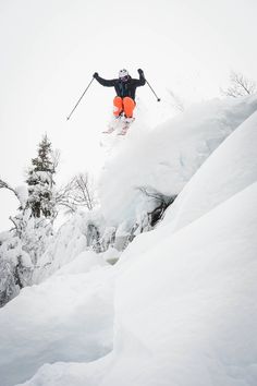 a person jumping in the air on skis while skiing down a snow covered hill