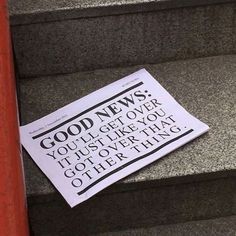 a newspaper laying on some stairs next to a red post with a sign that says good news you get over it