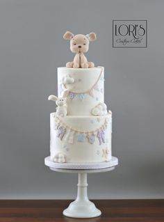 a three tiered cake with a teddy bear on top