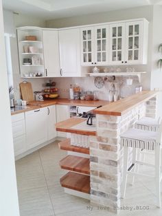 a kitchen with white cabinets and wooden counter tops, along with an island in the middle