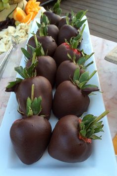 chocolate covered strawberries are arranged on a white platter, ready to be eaten