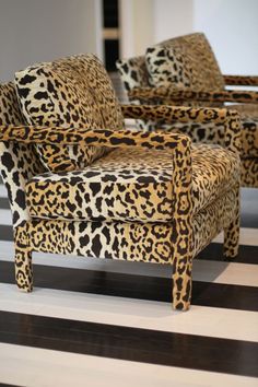 two leopard print chairs sitting on top of a black and white striped floor next to each other