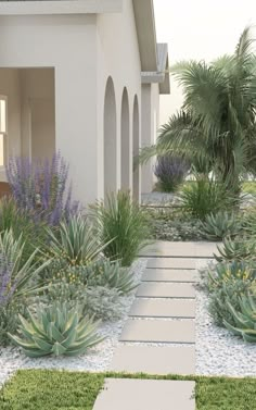 a white house with lots of plants in the front yard and walkway leading to it