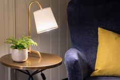 a small potted plant sits on a table next to a blue chair with a yellow pillow